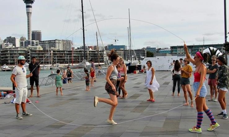 A group of people skip on Auckland's waterfront. In the background is the Sky Tower